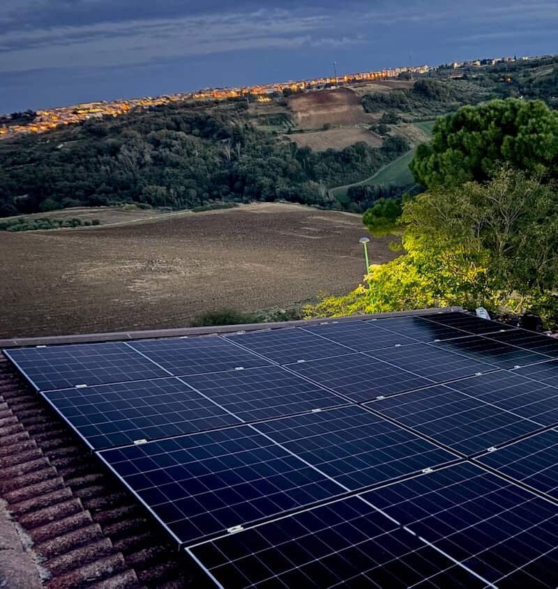 Pannelli solari installati su tetto in campagna con paesaggio collinare.